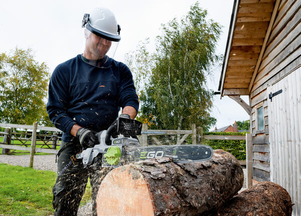 man using chainsaw on log