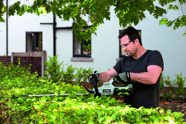man using cordless hedge trimmer